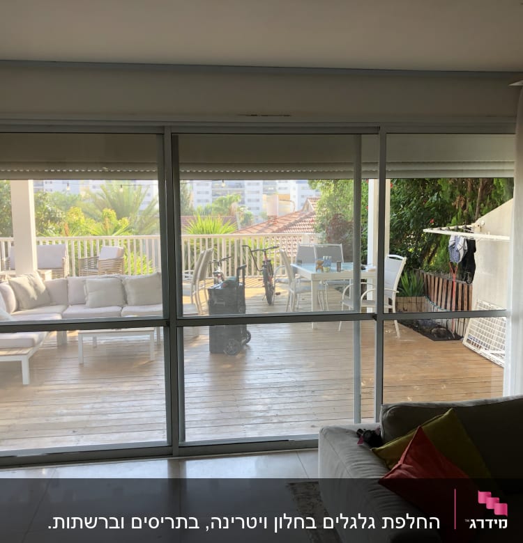 תריסים לבנים על חלון זכוכית גדול בסלון